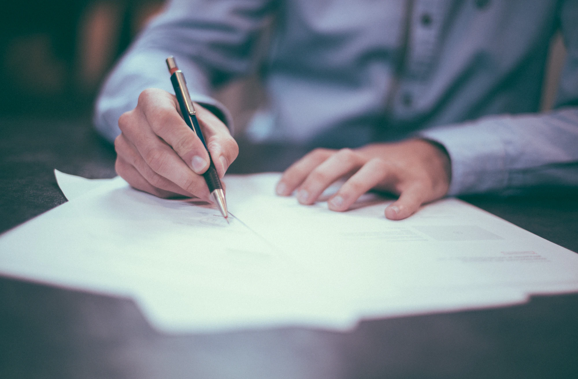 Manager signing compliance paperwork with a fountain pen